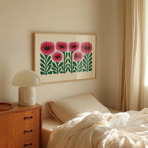 May include: A framed print of a stylized floral design featuring pink and red flowers with black centers and green leaves on a cream background.