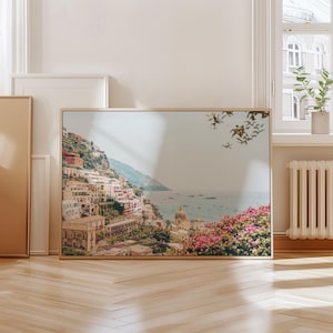 May include: A framed photograph of a coastal town with colorful buildings on a hillside overlooking a blue ocean. The photo is taken from a high vantage point, showing the town's architecture and the surrounding landscape.