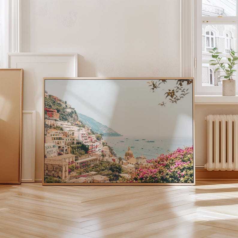 May include: A framed photograph of a coastal town with colorful buildings on a hillside overlooking a blue ocean. The photo is taken from a high vantage point, showing the town's architecture and the surrounding landscape.