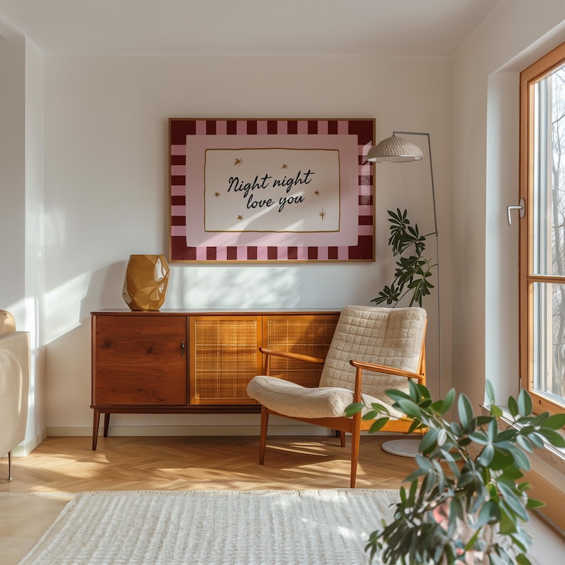 May include: A mid-century modern living room with a wooden cabinet, a beige armchair, and a framed artwork that reads "Night night love you." A gold vase and a floor lamp are also visible.