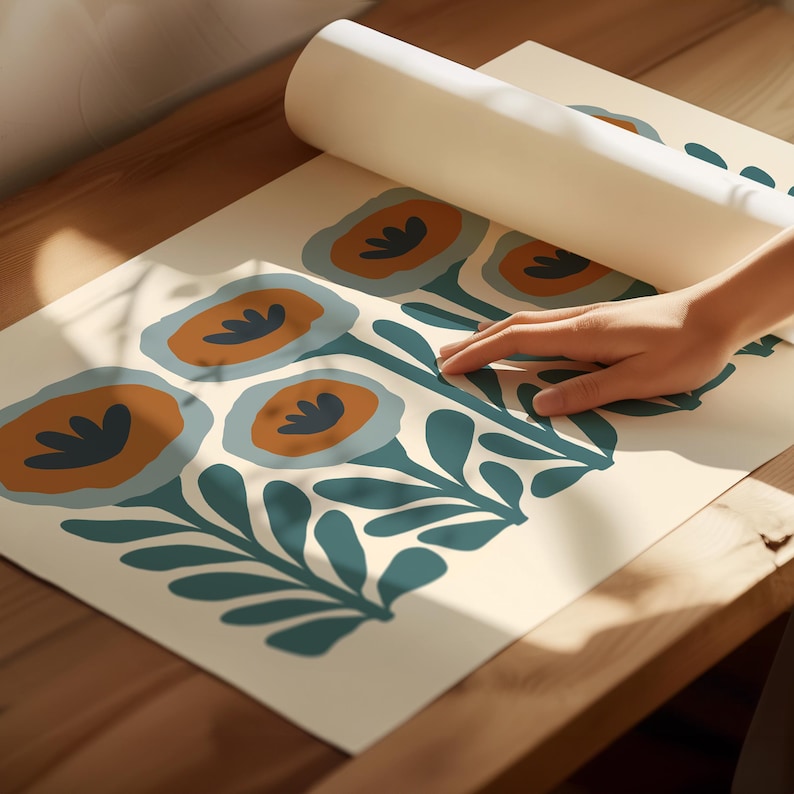 May include: A roll of floral wallpaper with a repeating pattern of stylized flowers in shades of orange, teal, and blue on an off-white background. The wallpaper is unrolled on a wooden surface.