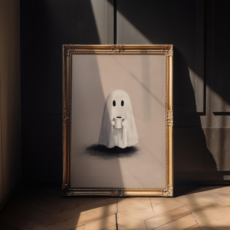 May include: A framed artwork featuring a whimsical ghost holding a coffee cup. The ghost is depicted in white against a light background, with a dark shadow beneath. The frame is ornate with a gold finish, adding a touch of elegance.