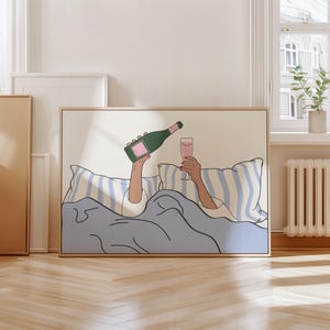 May include: A digital illustration of a person in bed with a glass of pink champagne and a bottle of champagne. The person is covered in a blue blanket and the bed has white and blue striped pillows.