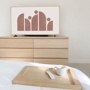 May include: A wooden tray with a white ceramic mug and a white remote control on a white bed. The tray is on top of a white bedspread.