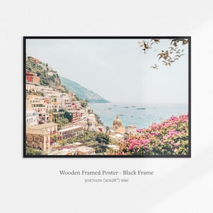 May include: A framed print of a coastal Italian town. The image features colorful buildings cascading down a hillside towards the sea. The print is in a black frame and measures 20x28 inches.
