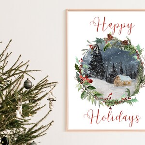 May include: A framed watercolor print with the words "Happy Holidays" in red script. The artwork depicts a snowy winter scene with a cabin nestled in a forest, surrounded by a wreath of greenery and red berries. A Christmas tree is in the foreground.