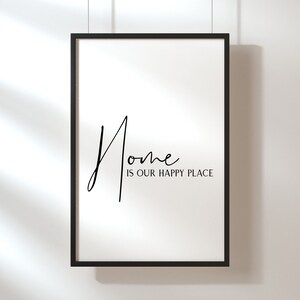 Op de afbeelding: Zwart-witte ingelijste print met de tekst "Home is our happy place" in een handschrift.