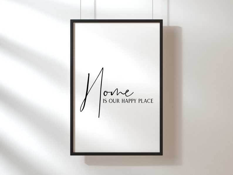 Op de afbeelding: Zwart-witte ingelijste print met de tekst "Home is our happy place" in een handschrift.