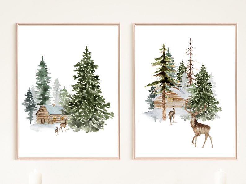 May include: Two framed watercolor prints depict winter scenes. One shows a cabin nestled among evergreen trees, with deer in the foreground. The other print features a similar cabin and trees, with deer. The artwork is in a soft, muted color palette.