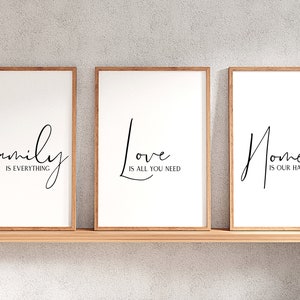 Op de afbeelding: Drie ingelijste prints met witte achtergronden en zwarte kalligrafie. De eerste print zegt "Family is everything". De tweede print zegt "Love is all you need". De derde print zegt "Home is our happy place".