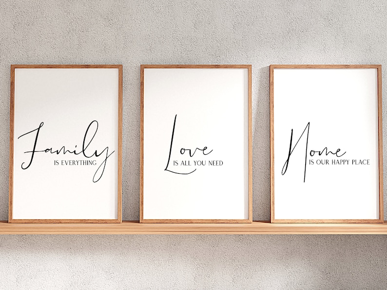 Op de afbeelding: Drie ingelijste prints met witte achtergronden en zwarte kalligrafie. De eerste print zegt "Family is everything". De tweede print zegt "Love is all you need". De derde print zegt "Home is our happy place".