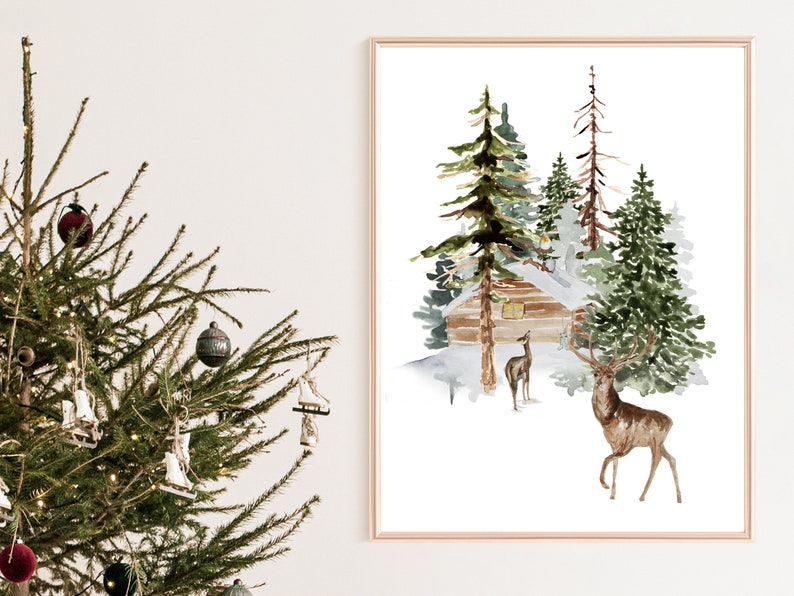May include: Watercolor painting of a winter scene with a cabin, evergreen trees, and deer. The artwork is framed in a gold-colored frame. The painting evokes a sense of peace and tranquility, perfect for holiday decor.