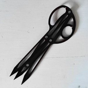 以下が含まれることがあります： ユニークなデザインの黒い金属製の折りたたみナイフ。ナイフは複数のブレードを持ち、コンパクトな形状に折り畳むことができます。