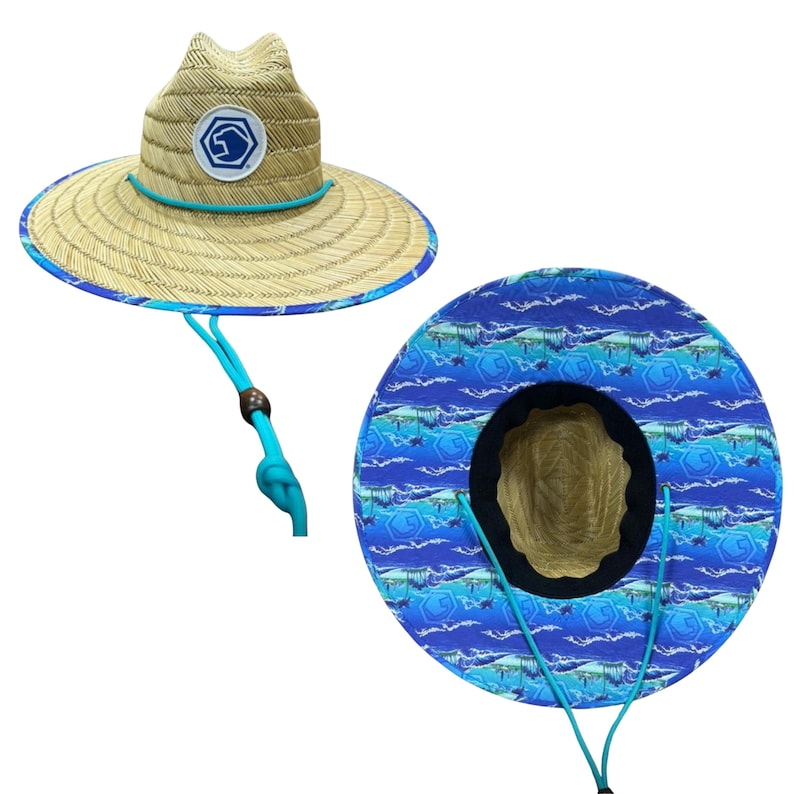 May include: A straw sun hat with a wide brim and a blue patterned underside. The hat features a blue chin strap and a patch with a logo. The brim is trimmed with blue. The hat's crown has a logo patch.