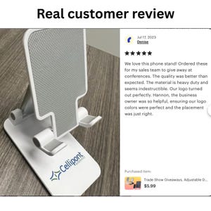 May include: White phone stand with a foldable design. The stand has a textured surface and a logo that says "Cellipont" in blue and white. The stand is on a wooden surface. The text "Trade Show Giveaways, Adjustable D... $5.99" is visible in the image.