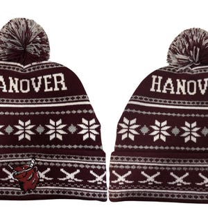 Pu&ograve; includere: Due berretti in maglia bordeaux con la scritta bianca "HANOVER". I berretti hanno un motivo a fiocco di neve e un pompon sulla parte superiore. Un berretto ha un logo bordeaux e bianco di un orso con mazze da hockey.