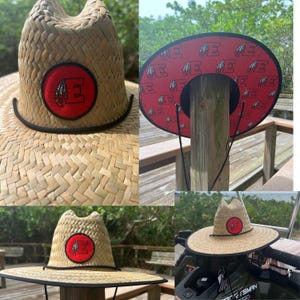 May include: A straw hat with a wide brim and a black band. The hat features a red circular patch with a white letter "E" and a Native American head graphic. The underside of the brim is red with white "E" logos.