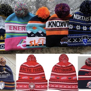 Pu&ograve; includere: Una collezione di berretti invernali con pompon. I berretti sono in vari colori, tra cui blu, rosso, arancione e grigio. Alcuni berretti hanno scritte come "YELLO", "ENER", "KNOXVI", "NORTHSTAR", "ARCTIC FOXES" e "PITTSBURGH".