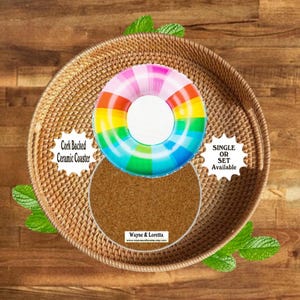 May include: A round ceramic coaster with a cork backing featuring a colorful rainbow-striped pool float design. The coaster displays the text "Cork Backed Ceramic Coaster", "SINGLE OR SET Available", and "Wayne & Loretta" on the surface.