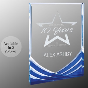 May include: A rectangular glass award with a blue and white wave design at the bottom. The text on the award reads "Celebrating 10 Years of Dedicated Service" and includes a star and the name "Alex Ashby."