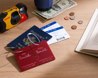 May include: Two rectangular red luggage tags with white wire loops, featuring the engraved text MR. Smith and MRS. Smith, along with placeholder email and phone number fields. The tags are positioned next to a blue United States passport.
