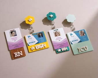 May include: Four badge reels with flower-shaped tops and attached identification cards. The reels feature various colors including yellow, teal, and light green, with white lettering such as RN, BSN, and ICU on the attached acrylic name plates.