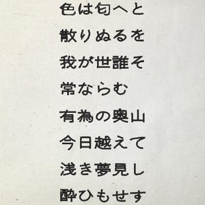 Könnte beinhalten: Eine weiße Leinwand mit schwarzem japanischem Text, der vertikal angeordnet ist. Der Text scheint ein Gedicht oder ein Zitat zu sein, wobei jede Zeile zentriert und gut platziert ist. Die Leinwand hat eine leicht strukturierte Oberfläche.