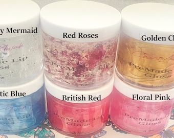 May include: Six small jars of lip gloss in various colors, including red, blue, pink, and gold. Each jar has a white lid and a label that reads "PreMade Lip Gloss" and "4 oz". The jars are arranged in two rows of three.