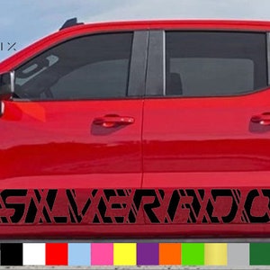 Puede incluir: Una camioneta roja con una calcomanía negra "SILVERADO" en el lateral. La calcomanía tiene un patrón geométrico.