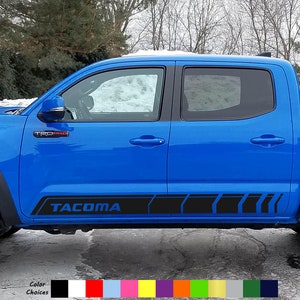 May include: A blue Toyota Tacoma pickup truck with black side decals that say "TACOMA".