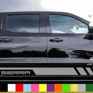 May include: Black pickup truck with a grey and black "SIERRA" decal on the side. The decal has a grey stripe with black accents. The truck has a black grille and black wheels. The image shows a variety of colour options for the decal.