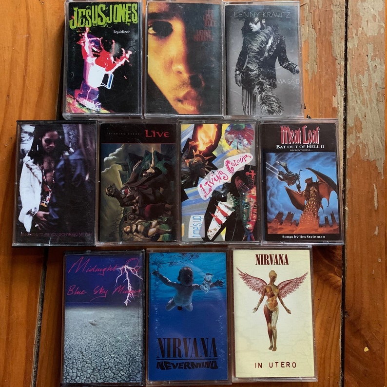 May include: A collection of nine cassette tapes, including albums by Jesus Jones, Lenny Kravitz, Meat Loaf, Nirvana, and Living Colour. The tapes are arranged in three rows, with the titles and artist names visible.