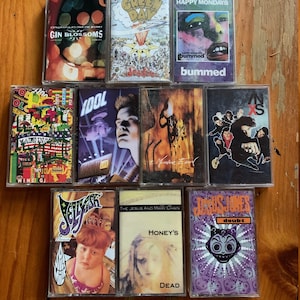 May include: A collection of 10 cassette tapes with various band names and album titles. The tapes are arranged in two rows, with five tapes in each row. The tapes are all different colors and have different designs. Some of the tapes have images on them, while others have text. The tapes are all in good condition and appear to be vintage.