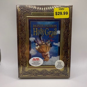 Peut inclure: Un coffret DVD de Monty Python et le Sacré Graal, présenté dans un cadre doré. Le coffret comprend trois disques et une piste audio française. L'étiquette de prix indique 29,99 €.