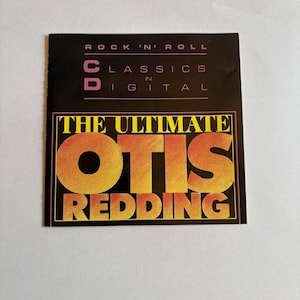 May include: A CD case with a black background and the text "ROCK 'N' ROLL CLASSICS IN DIGITAL". The title "THE ULTIMATE OTIS REDDING" is in large orange and yellow letters.