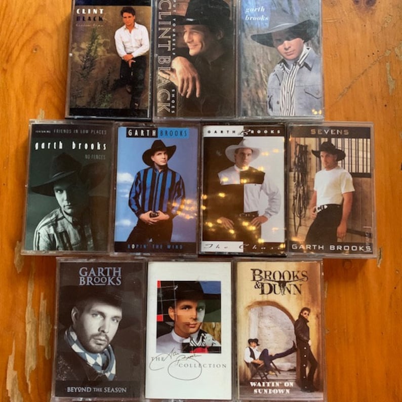 May include: A collection of eight cassette tapes featuring country music artists Garth Brooks, Clint Black, and Brooks & Dunn. The tapes are in clear plastic cases with colourful artwork and text. The titles of the tapes include "Friends in Low Places", "No Fences", "The Chase", "Sevens", "Beyond the Season", "The Collection", and "Waitin' on Sundown".