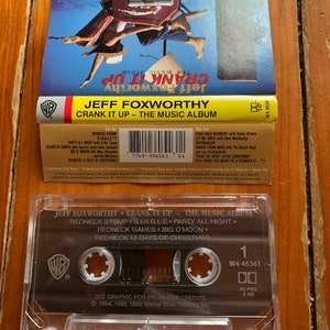 May include: A cassette tape of Jeff Foxworthy's album "Crank It Up - The Music Album". The cassette tape is black with a white Warner Bros. Records logo. The cassette tape is labeled with the album title and the track list: "Redneck Stomp", "S.I.N.G.L.E", "Party All Night", "Redneck Games", "Big O'Moon", and "Redneck 12 Days of Christmas".