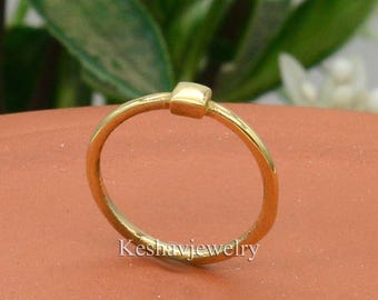 May include: A simple gold ring with a square-shaped accent. The ring is made of a thin band of metal and has a minimalist design.