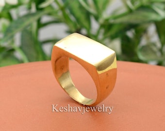 Könnte beinhalten: Ein goldfarbener, rechteckiger Ring. Der Ring ist aus Metall und hat eine glatte, polierte Oberfläche.