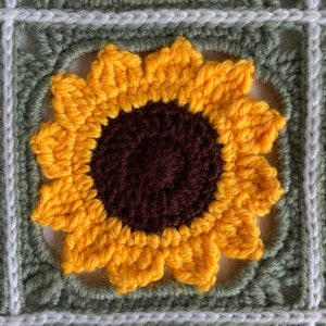 May include: A crocheted sunflower with yellow petals and a brown centre, framed by a green and white crocheted square.