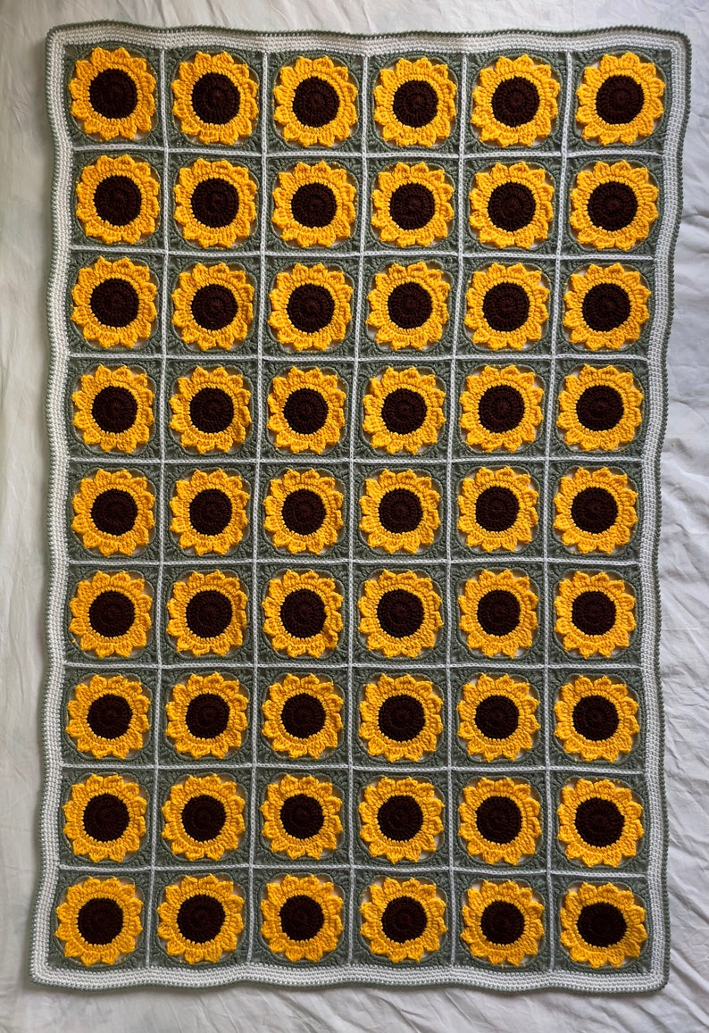 May include: A crocheted blanket featuring a sunflower design. The blanket is made from green and yellow yarn and has a repeating pattern of sunflowers with brown centres.