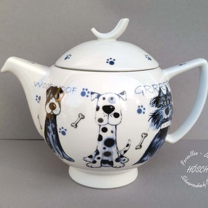 Könnte beinhalten: Weiße Keramik-Teekanne mit Deckel, Henkel und Ausguss. Die Teekanne ist mit Cartoon-Hunde-Illustrationen, Pfotenabdrücken und den Worten "WOOF WOOF" und "GRRRR" verziert. Sie hat einen geschwungenen Griff.