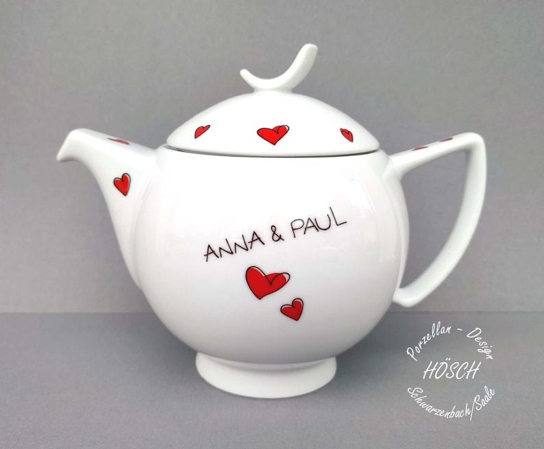 Puede incluir: Tetera de porcelana blanca con un dise&ntilde;o de coraz&oacute;n rojo y el texto "ANNA & PAUL".