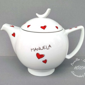 Puede incluir: Tetera de porcelana blanca con un dise&ntilde;o de corazones rojos y el nombre "MANUELA" escrito en el lateral. La tetera tiene una tapa con un asa en forma de p&aacute;jaro y est&aacute; decorada con corazones rojos. La tetera est&aacute; hecha por H&Ouml;SCH Schwarzenbach/Saale.