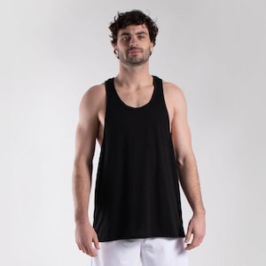 Puede incluir: Una camiseta sin mangas negra con cuello redondo. La camiseta sin mangas está hecha de un material suave. El modelo lleva pantalones cortos blancos. La camiseta sin mangas es una prenda versátil para uso casual o entrenamientos.