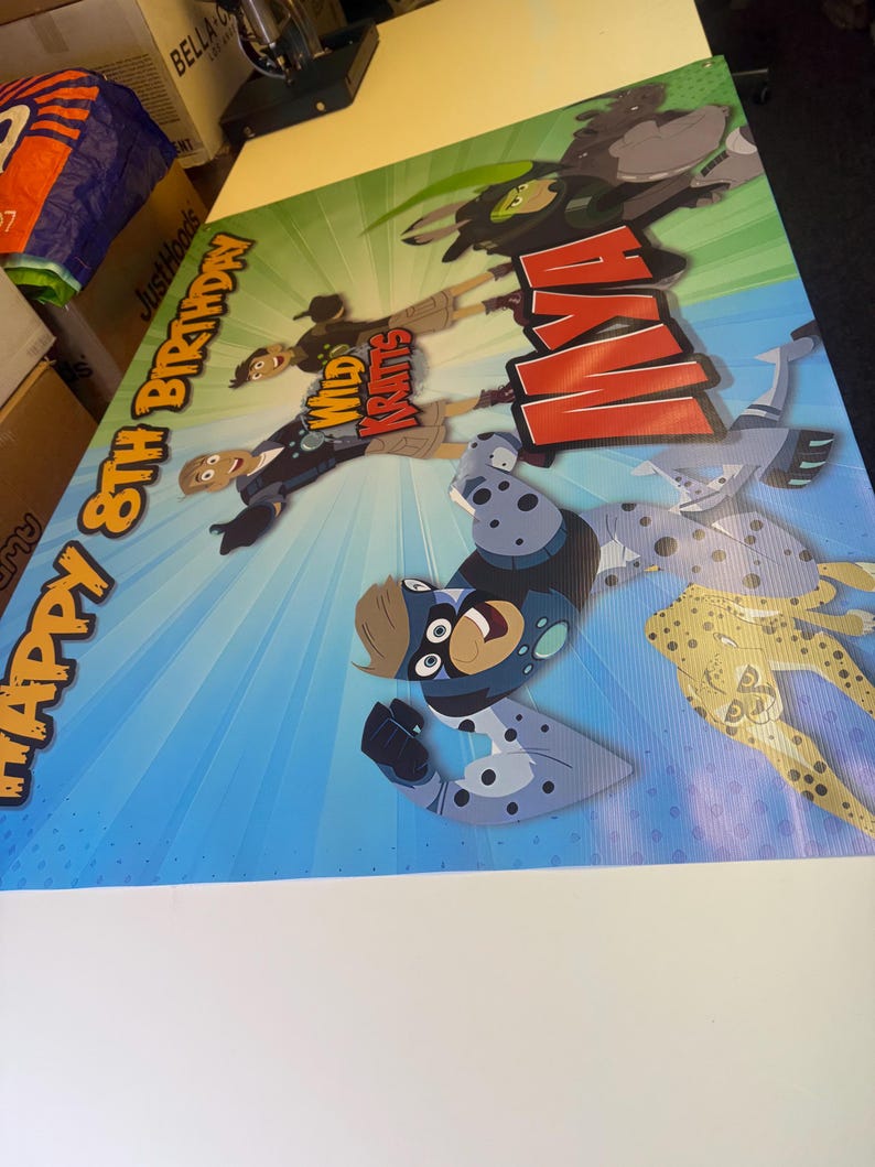 May include: A colorful birthday banner featuring the Wild Kratts characters. The banner has a blue and green background with a red and white "Happy 8th Birthday" message. The characters are depicted in their animal suits, including a cheetah, a leopard, and a monkey.