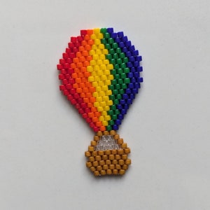 Könnte beinhalten: Ein regenbogenfarbener Heißluftballon aus kleinen Perlen mit einem braunen Perlenkorb.