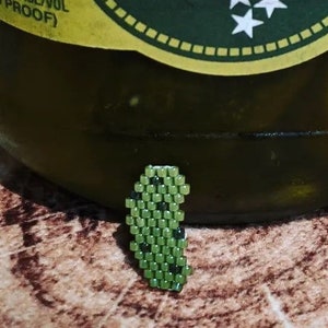Könnte beinhalten: Ein Glas mit grünen Gurken, das ein gelbes Etikett mit der Aufschrift "Ole Smoky Tennessee Moonshine" und "Moonshine Pickles" trägt.