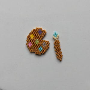 May include: A small, brown, beaded paint palette with colorful beads and a matching brown beaded paintbrush.