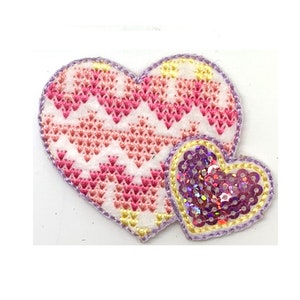 May include: Two heart-shaped patches, one with a pink and white chevron pattern and the other with purple sequins.